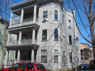 A three-story triple-decker house in Cambridge with stacked front porches